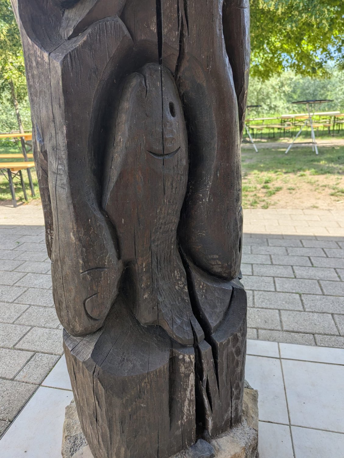Detailaufnahme eines handgeschnitzten Fisches in einer Holzsäule