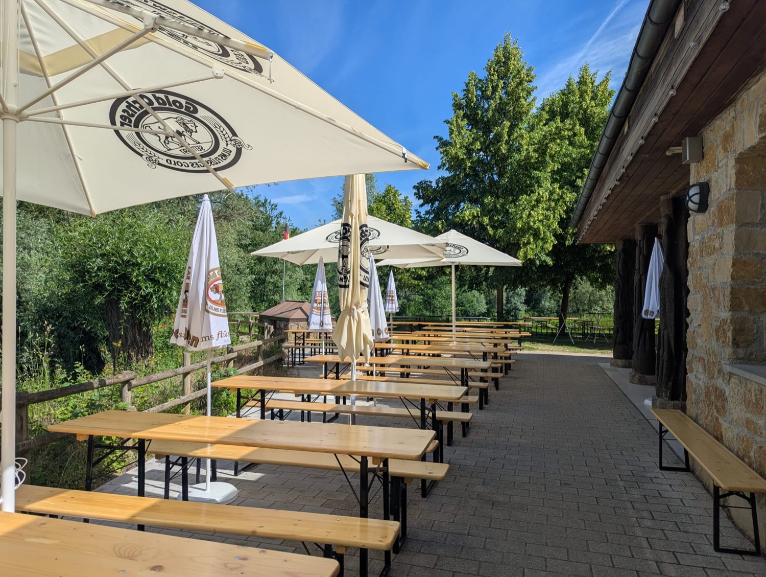 Sitzplätze mit Sonnenschirmen entlang der steinernen Gebäudewand