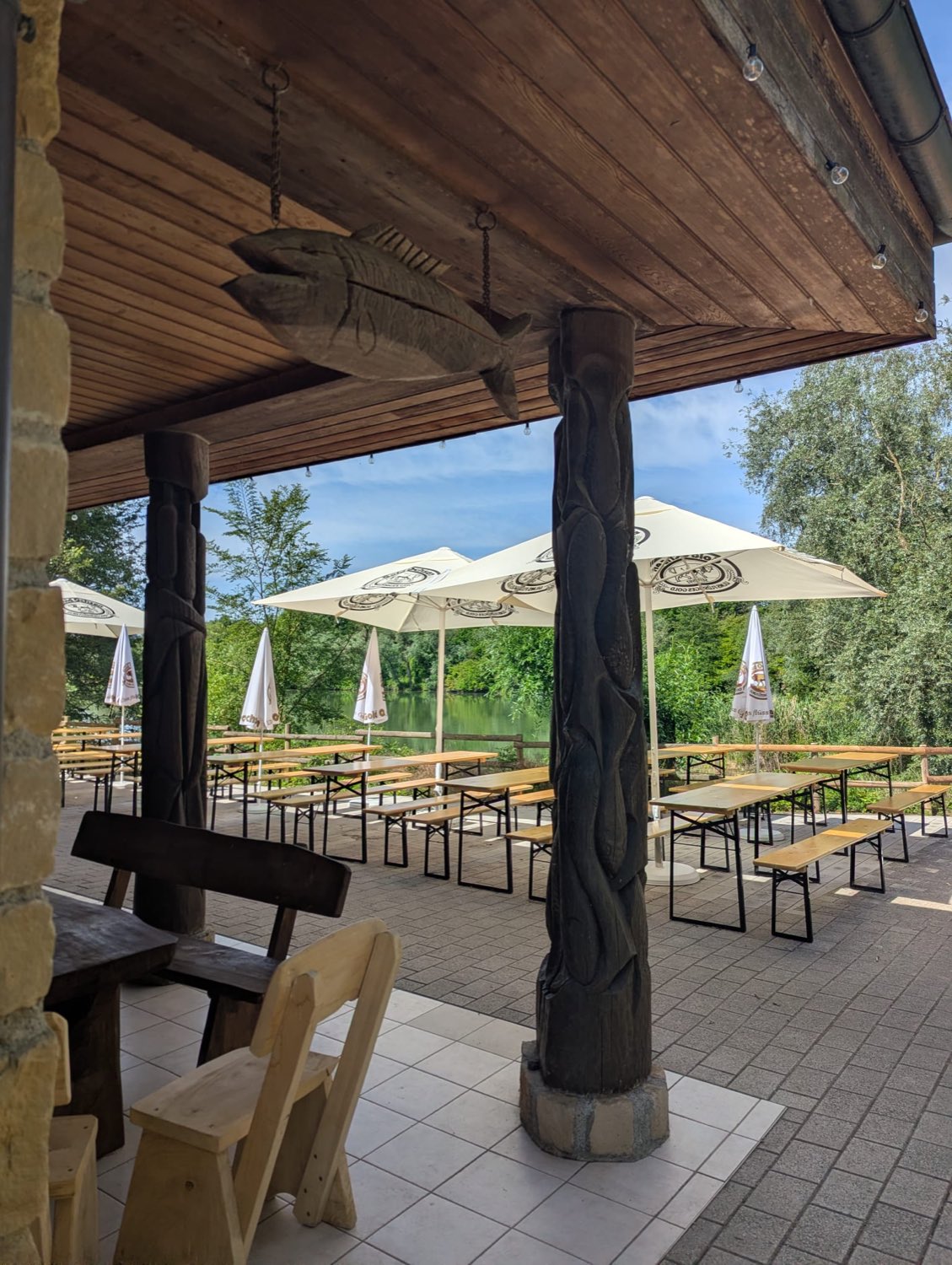 Überdachte Terrasse mit geschnitzter Holzsäule und Blick auf den See