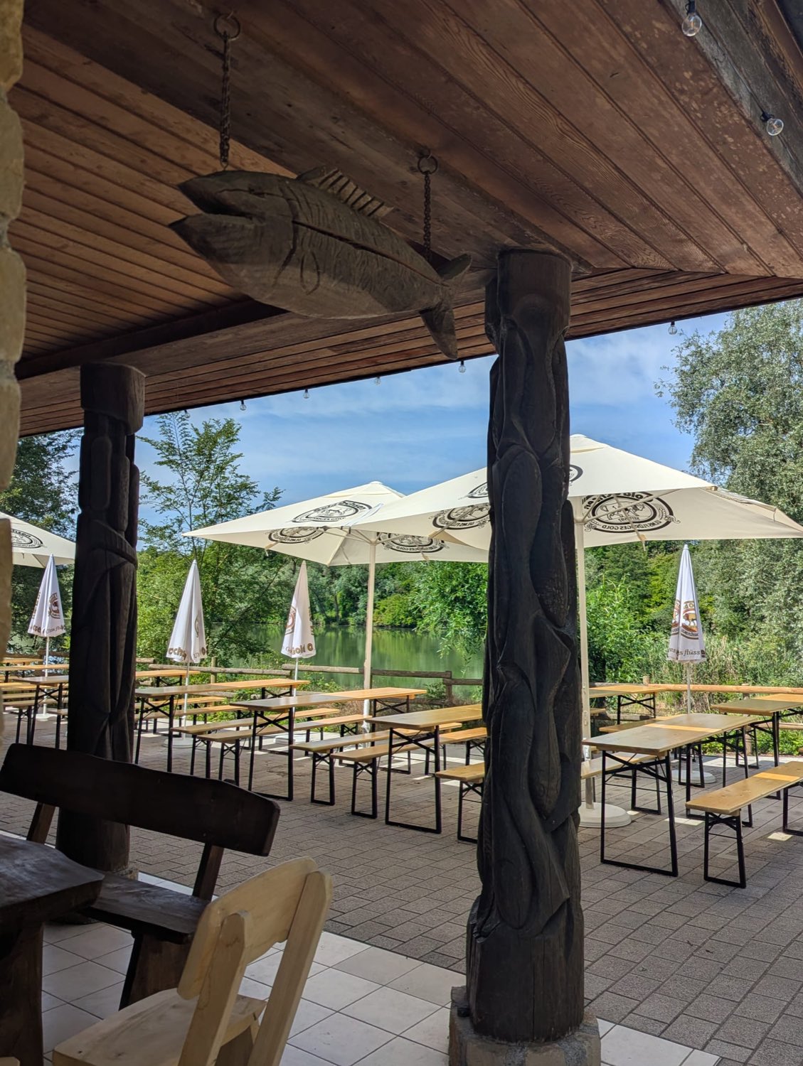 Überdachte Terrasse mit Sonnenschirmen und Blick auf den See
