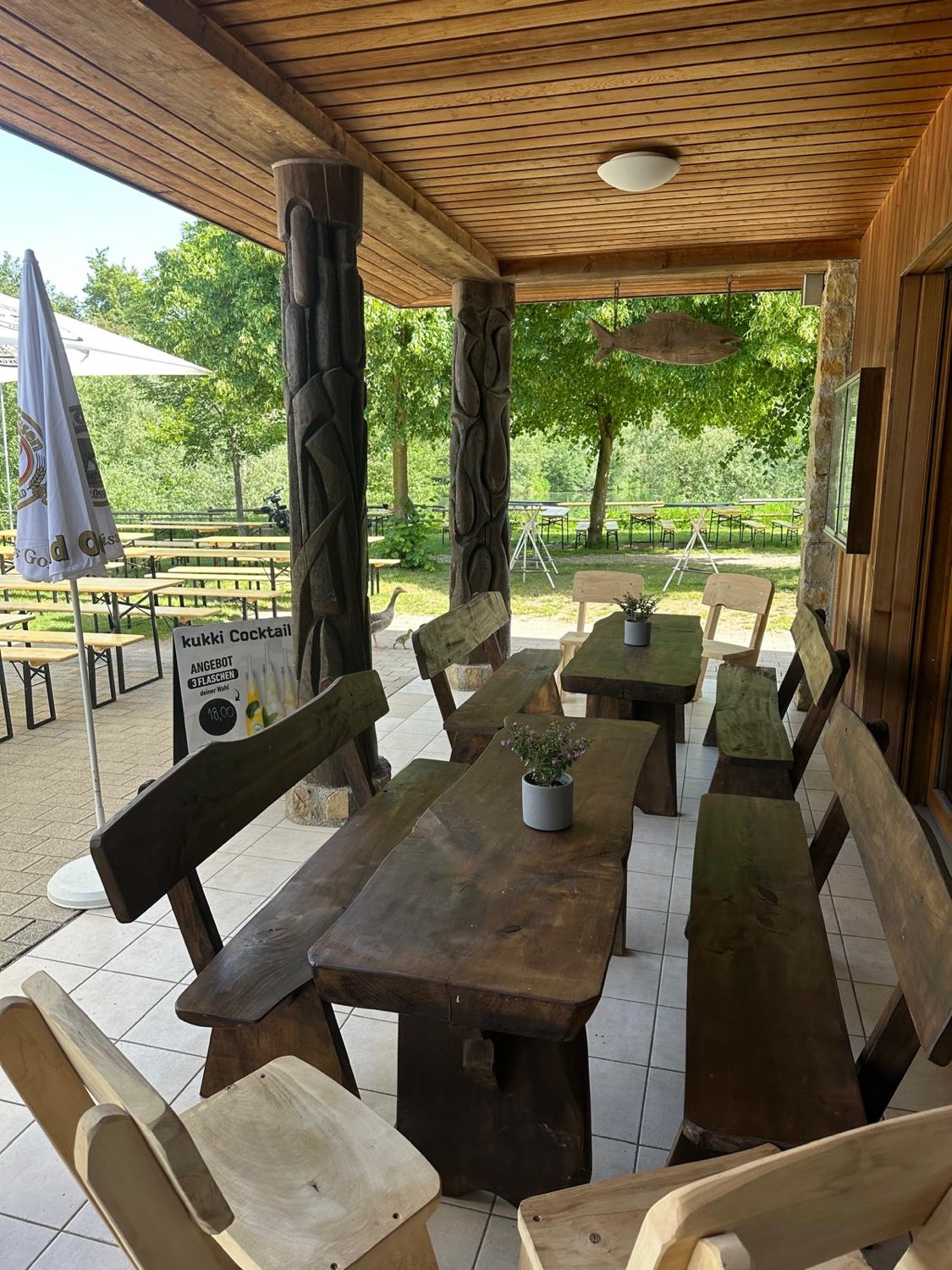 Rustikale Sitzecke mit Holztischen unter der Terrasse