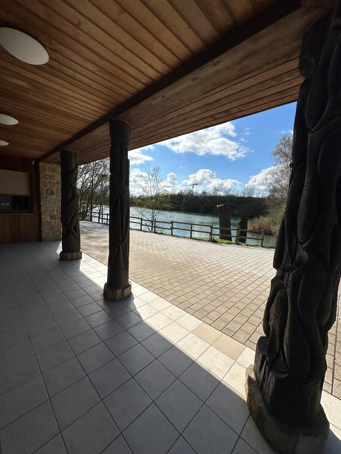 Terrasse mit geschnitzten Totempfählen und Blick auf den See