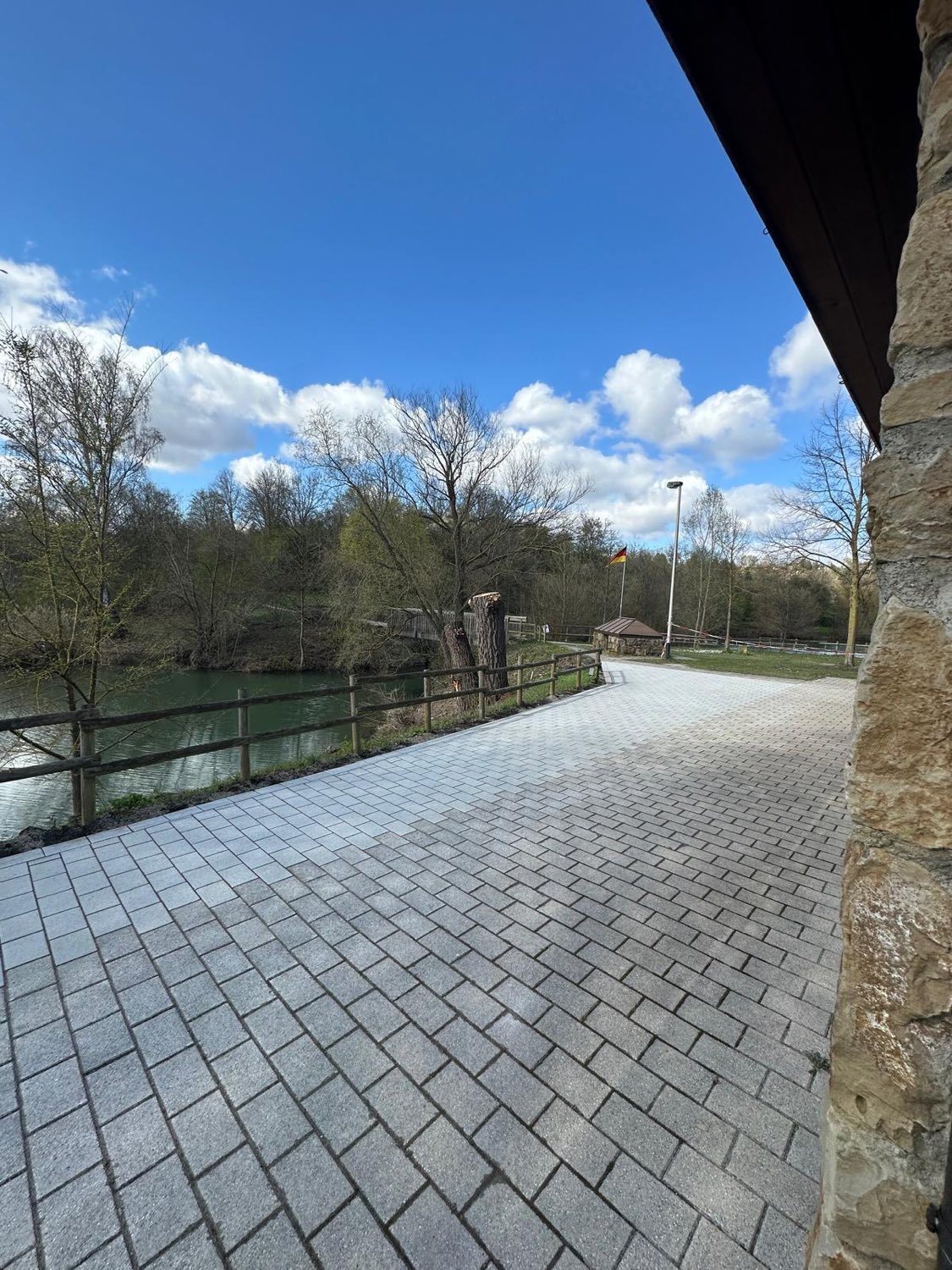 Gepflasterter Weg an der Fischerhütte mit Blick auf den See und den Neckartal-Radweg